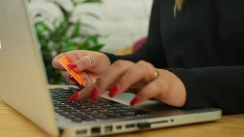 Close up of an unrecognizable woman paying online using a credit card and a laptop