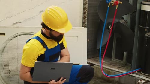 HVAC Technician Using Laptop for AC Repair