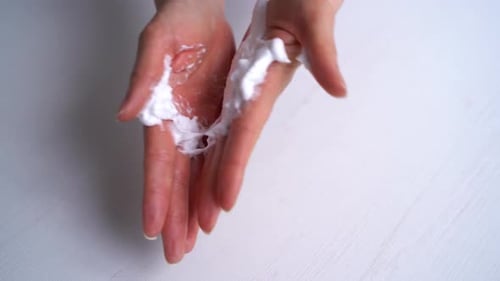 Femme méconnaissable frottant de la crème dorlotante sur ses mains Gros plan