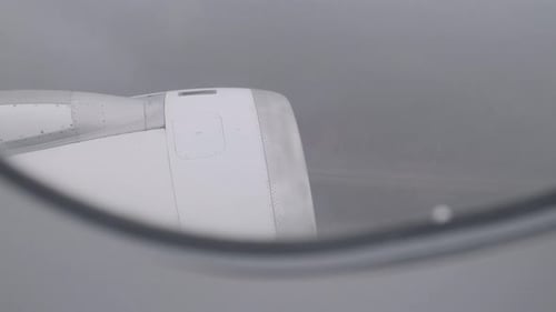 Close-up view of airplane engine through window during overcast in-flight moment