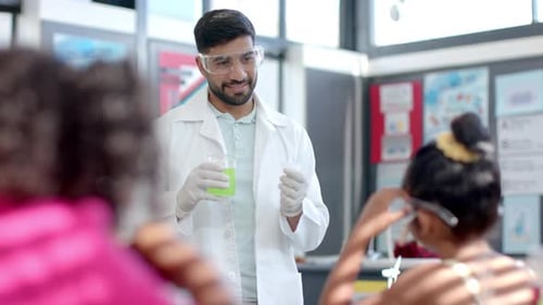In a school classroom, a young biracial teacher demonstrates a chemistry experiment