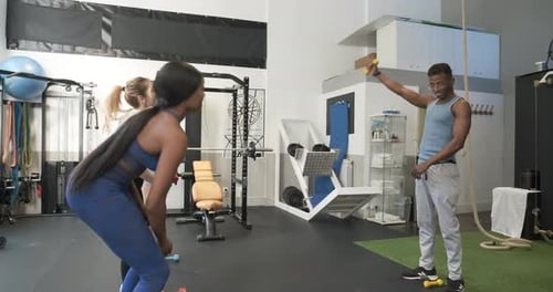Instructor Giving a Fitness Class Using Dumbbells at Modern Gym