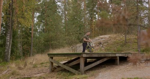 Disc golfer approaches a tee in the forest and inspects course - wide shot