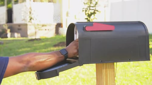 Black man opening a mail box and receiving mail