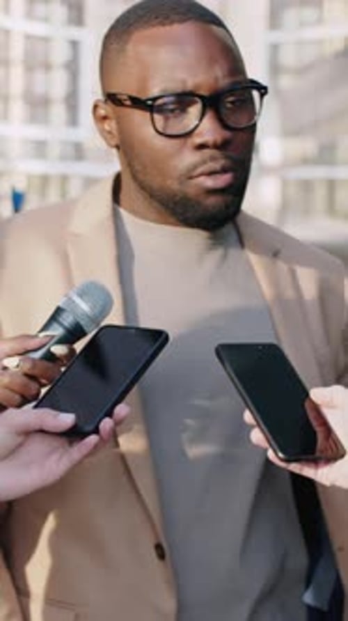 Man in Blazer Giving Interview to Reporters Outdoors