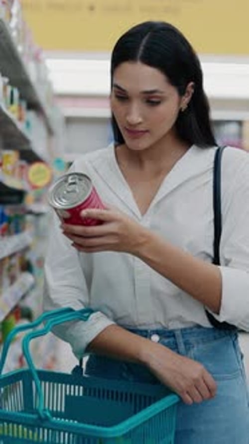 Vertical Video Cute Woman Holding A Packaged Product In The Store To Read The Ingredients