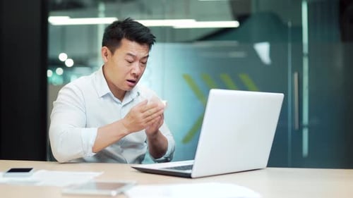 Man Blowing His Nose In An Office
