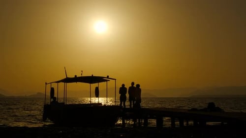 Sunset Silhouette of People on Pier with Boat