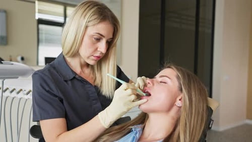 Mujer que recibe un procedimiento dental mientras el dentista examina los dientes en la clínica