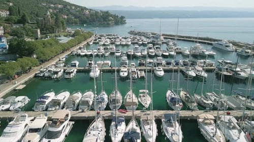 A marina filled with yachts and sailboats on a sunny day, aerial view