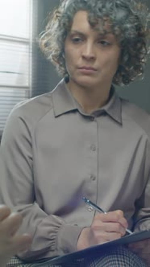Woman Talking in an Office with a Clipboard