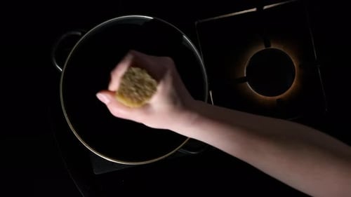 Man cooking pasta. Hand of chef throwing spaghetti into pot on kitchen stove, top view.