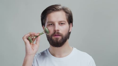 Man Using Jade Roller on Face for Skincare