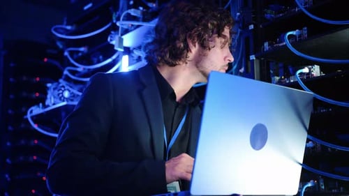 Man analysing servers and programming on a computer in a data center