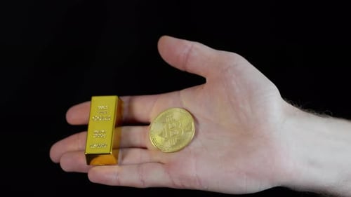 Person Holding Gold Bar and Bitcoin in Hand, Close up on Black Background