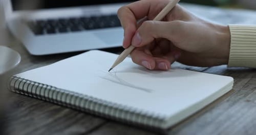 Hand Drawing in Notebook on Wooden Desk