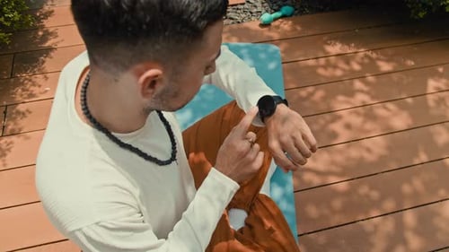 Sportsman Looking at Smartwatch Meditating on Mat