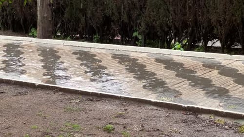 nasser Kopfsteinpflasterweg, der bei Regen mit Wasser bedeckt ist
