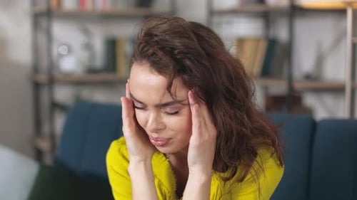 Caucasian Female Suffering From Headache in Living Room