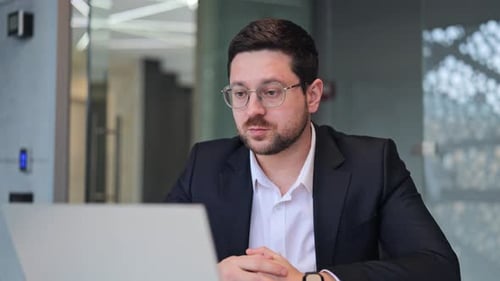 Professional Man Talking on Laptop in Modern Office