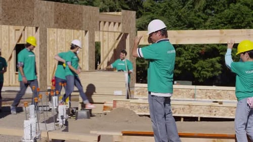 Volunteers Carry Lumber at Construction Site on Sunny Day
