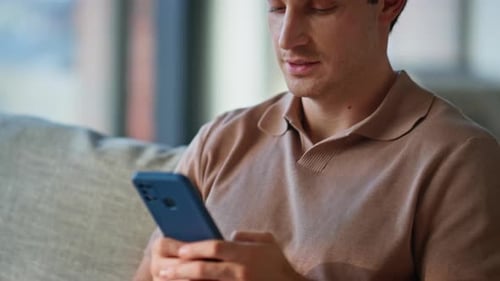 Young Man Using Smartphone on Couch Indoors