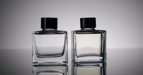 Elegant Glass Perfume Bottles with Black Caps on Reflective Surface