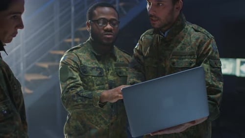 Military Personnel Reviewing Laptop Data in Control Room