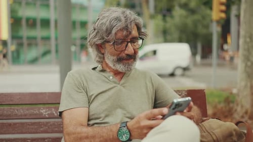 Man with Gray Hair Using Phone on Bench