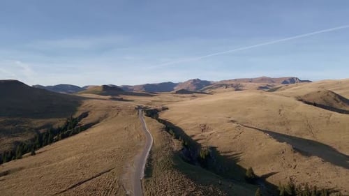 Une vue aérienne pittoresque d'une route sinueuse traversant les collines dorées de la Roumanie, sur