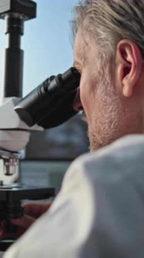 Man Looking Through Microscope in a Lab