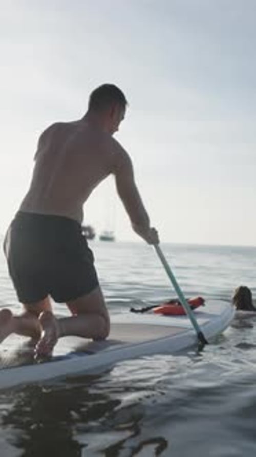 Rear Shot of a Couple Paddle Surfing in the Sea Water in Thailand