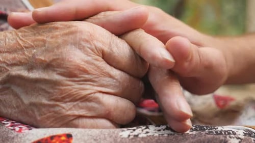 Close Up of Young Male Hand Comforting an Elderly Arms of Old Woman Outdoor
