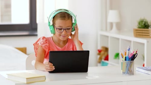 Girl with headphones using tablet at desk