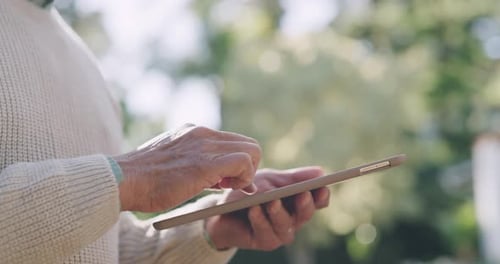 Person browsing on tablet in nature, typing a text message and scrolling on social media