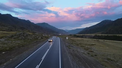 Vue aérienne d'une vallée avec une rivière et une route entourée de montagnes au coucher du soleil