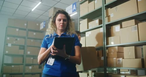 Female Logistics Specialist Uses Tablet Computer and Stylus Checks Inventory