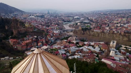 Aerial forward flight over Tbilisi old town and river with church dome