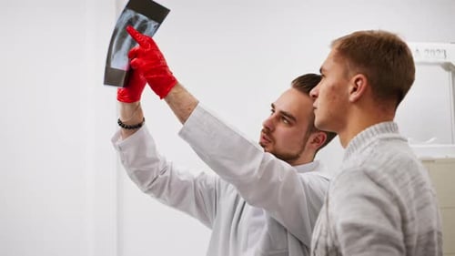 Close Up in a Private Clinic in White Xray Room the Doctor Shows the Patient a Picture of the Back