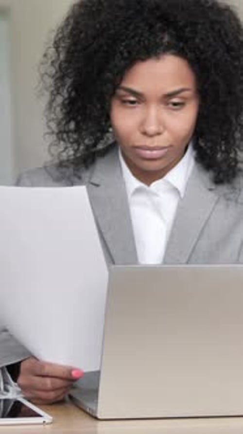 Business Woman Reviews Documents at Desk in Office