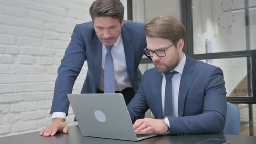 Men Collaborate on Laptop in Modern Office