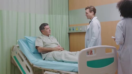 Friendly Doctor, Nurse Discussing Elderly Patient Health in Hospital