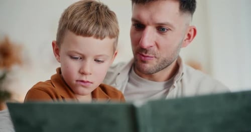 Un niño y su padre miran fotos de sus antepasados en un álbum familiar