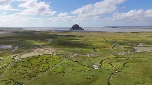 Flight over green fields near Mont-Saint-Michel tidal island in Normandy, France