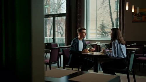 Date in the hotel restaurant dinner man and woman drink white wine in glasses and taste food