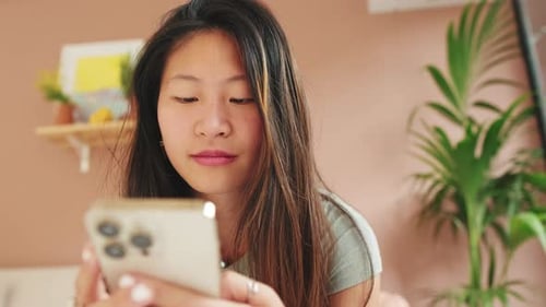 Close-up, young woman sitting on the sofa writes SMS with a mobile phone