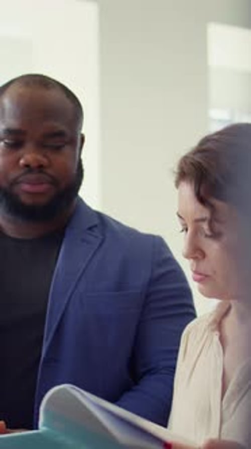 Vertikales Videoporträt zufriedener Kunden im Autohaus beim Stöbern im Automobilkatalog