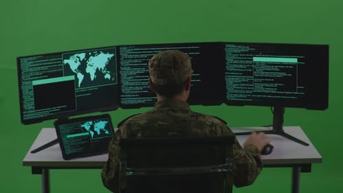 Back View Of Man Soldier Working With Tablet While Write Code With Multiple Screens In Green Screen