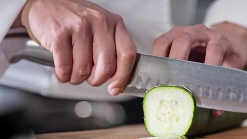 Chef slicing cucumber in slow motion