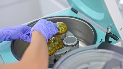 Hands in blue latex gloves put the test tube with blood into apparatus.